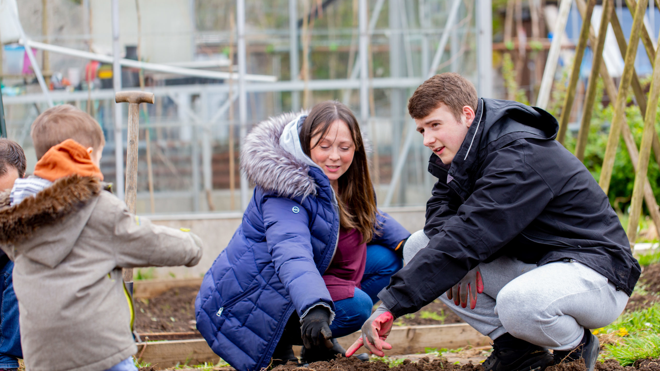 An adolescent boy and an adult woman with garden gloves on their hands