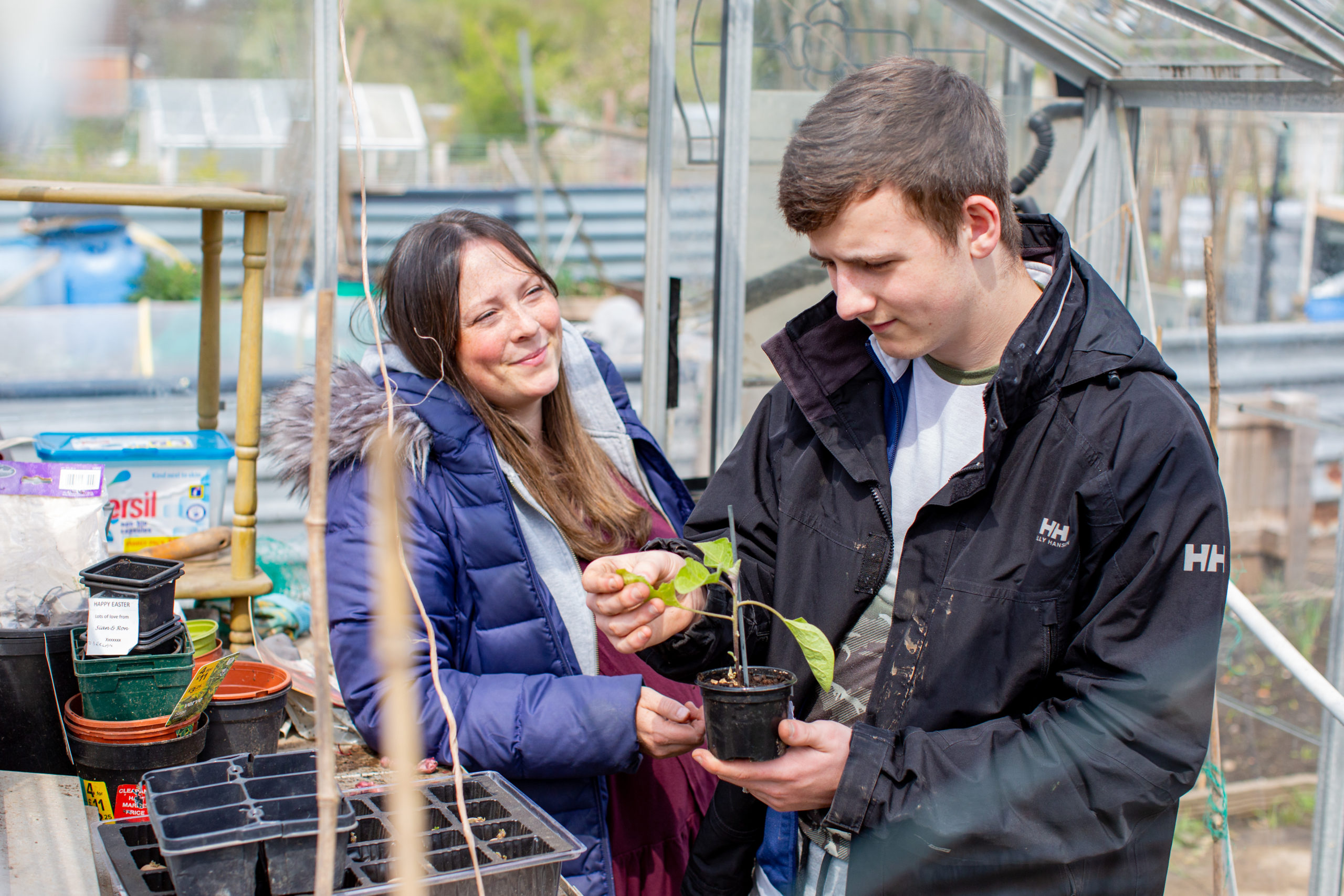 Woman smiling and supporting teenage boy gardening