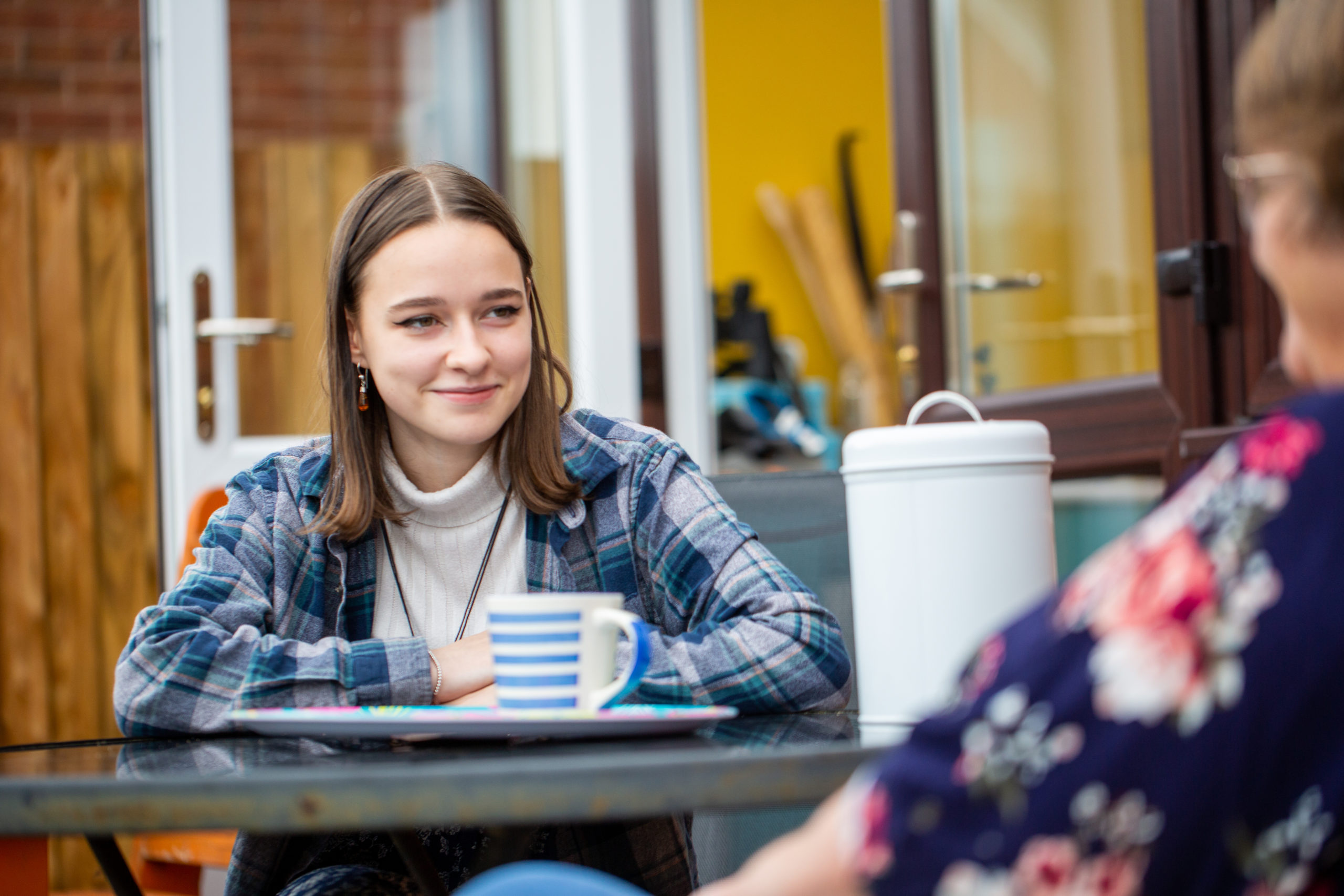 Teenage girl sat at table outside smiling