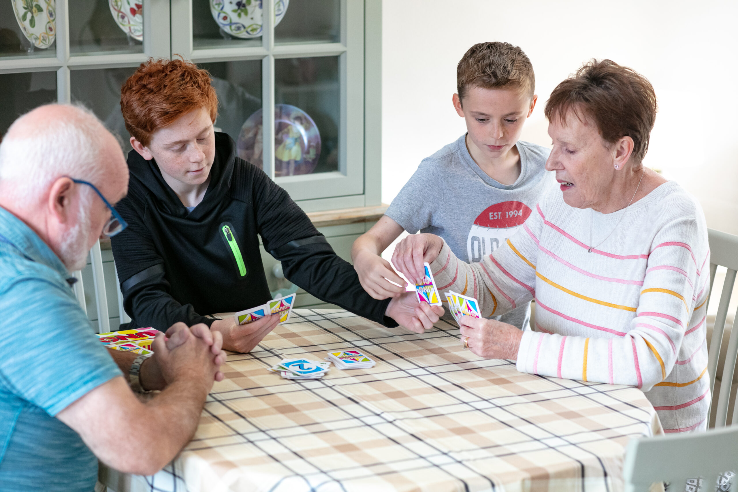 An older couple playing a card game with two boys at a table
