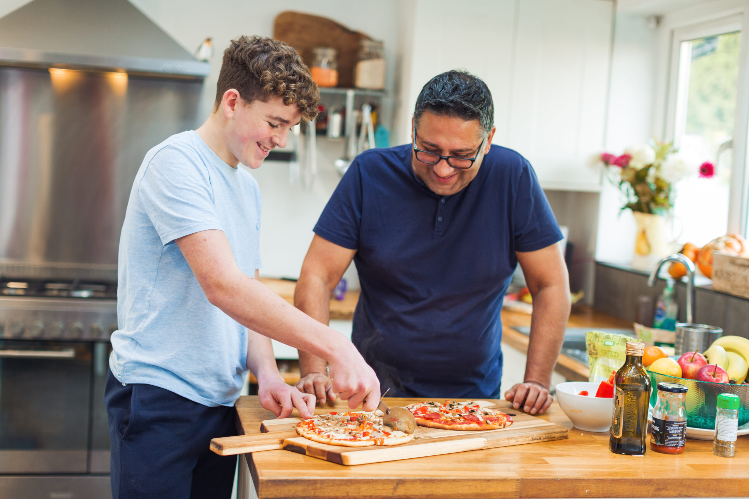 Fostered teen cutting pizza with foster parent